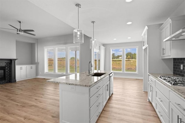5005 146th St, Basehor, KS 66007 - kitchen featuring appliances with stainless steel finishes, light wood finished floors, ceiling fan, open floor plan, and wall chimney range hood
