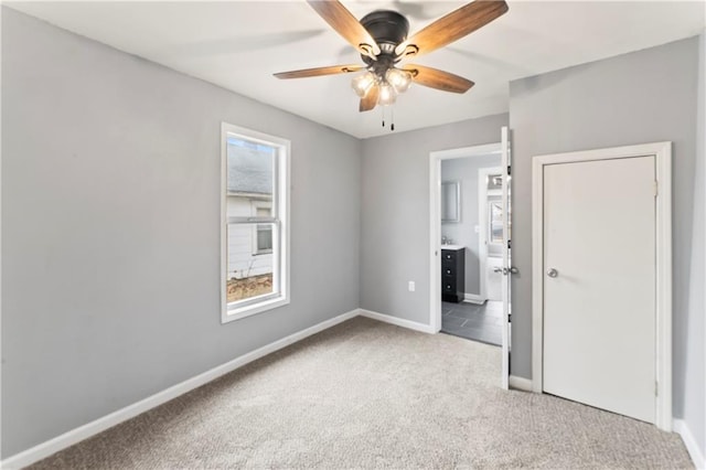 unfurnished bedroom featuring ceiling fan, light carpet, and ensuite bath