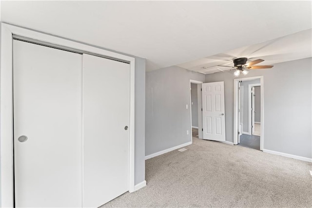 unfurnished bedroom featuring light colored carpet, ceiling fan, and a closet