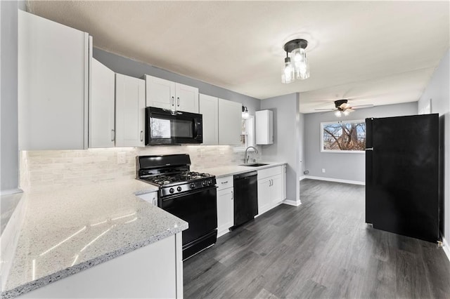 kitchen with light stone counters, sink, white cabinetry, and black appliances