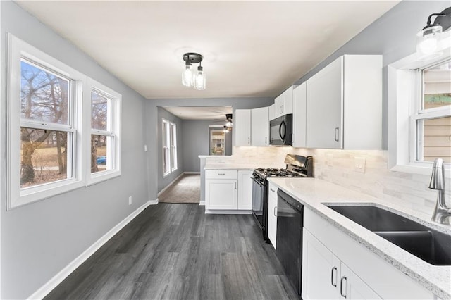 kitchen with sink, white cabinets, decorative backsplash, light stone counters, and black appliances