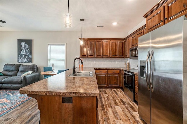 kitchen featuring tasteful backsplash, pendant lighting, wood-type flooring, sink, and stainless steel appliances