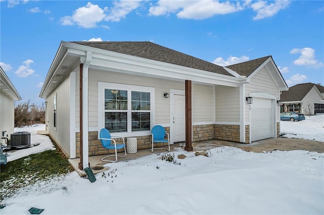 1740 S Park Dr, Tonganoxie, KS 66086 - view of front of home with a garage, central AC unit, roof with shingles, and stone siding