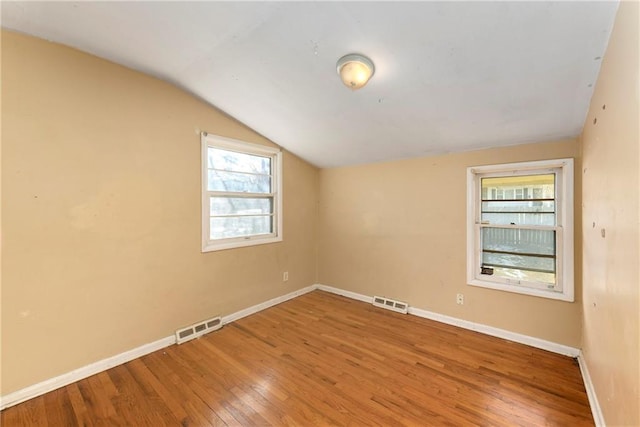 spare room featuring hardwood / wood-style flooring and vaulted ceiling