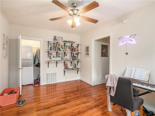 office with hardwood / wood-style flooring, ceiling fan, and stacked washer and clothes dryer