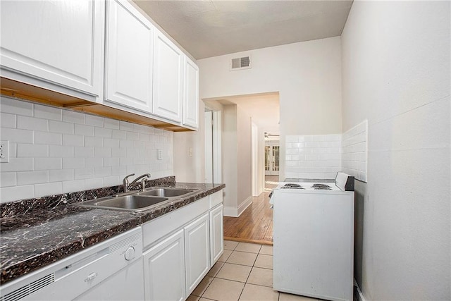 kitchen featuring white appliances, backsplash, sink, light tile patterned flooring, and white cabinetry