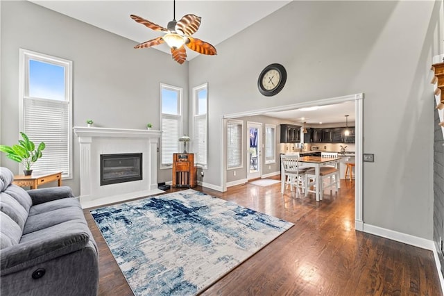 living room featuring a high ceiling, ceiling fan, and dark hardwood / wood-style flooring