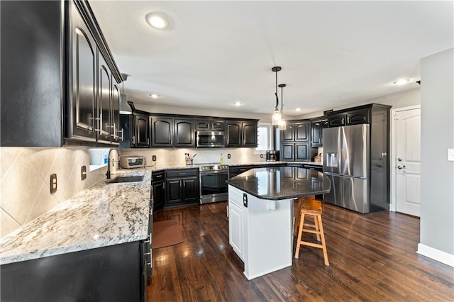 kitchen with a kitchen island, appliances with stainless steel finishes, sink, and dark hardwood / wood-style floors