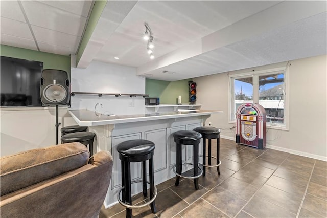 kitchen with dark tile patterned flooring, a kitchen breakfast bar, and kitchen peninsula