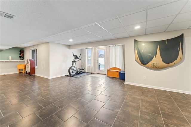 workout room with a drop ceiling and dark tile patterned flooring