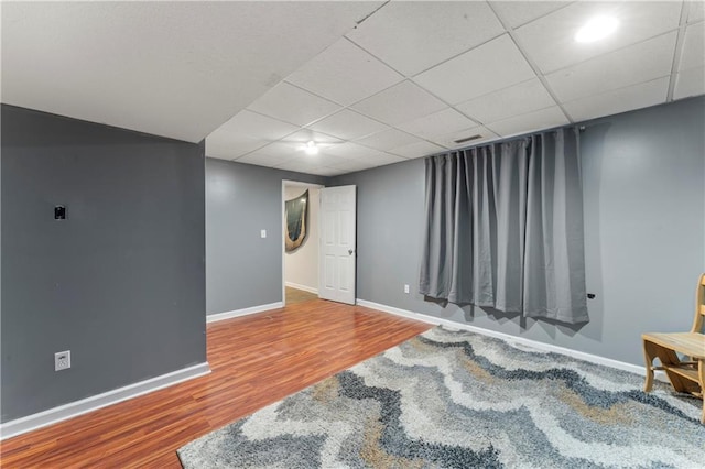 basement with a drop ceiling and hardwood / wood-style floors