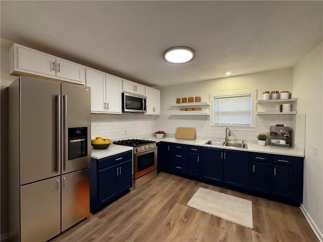 kitchen with light wood-type flooring, stainless steel appliances, sink, blue cabinetry, and white cabinets