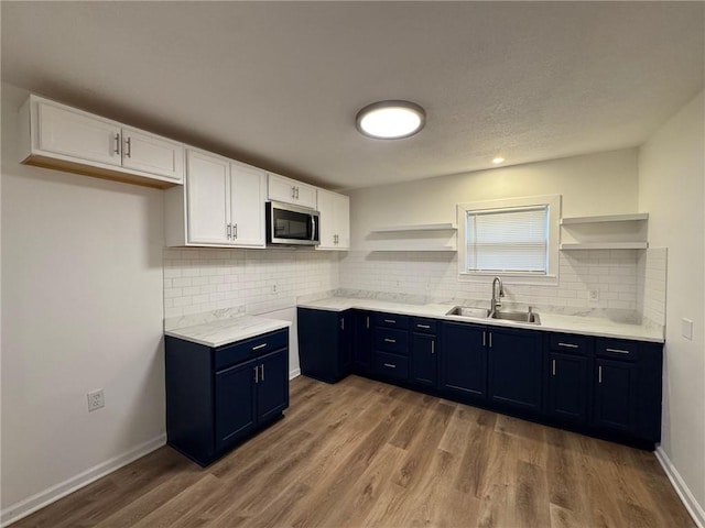 kitchen featuring blue cabinetry, wood-type flooring, sink, and white cabinets