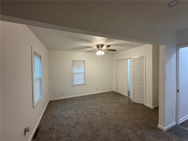 unfurnished bedroom featuring ceiling fan, a closet, and dark colored carpet