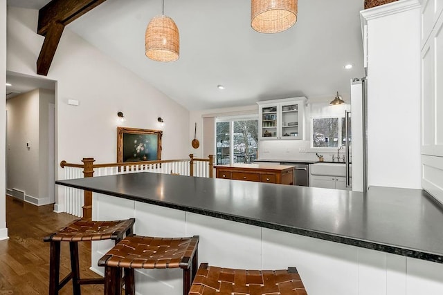 kitchen with dark countertops, glass insert cabinets, and white cabinetry