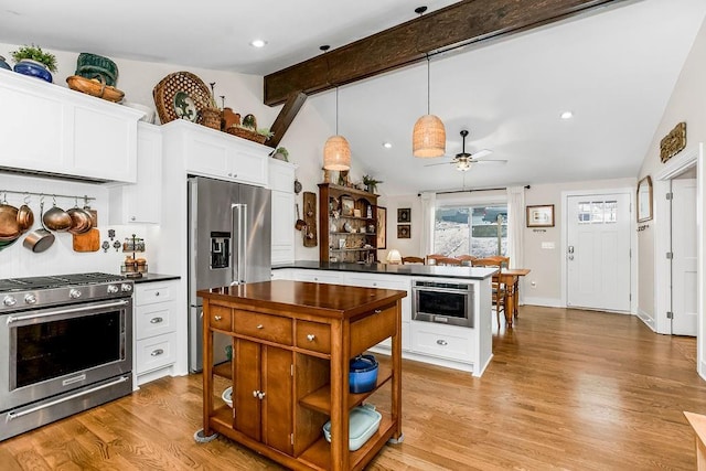 kitchen featuring dark countertops, vaulted ceiling with beams, light wood-style flooring, appliances with stainless steel finishes, and white cabinetry