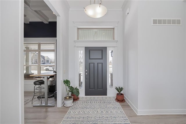 entrance foyer with crown molding, light hardwood / wood-style floors, beamed ceiling, and a towering ceiling