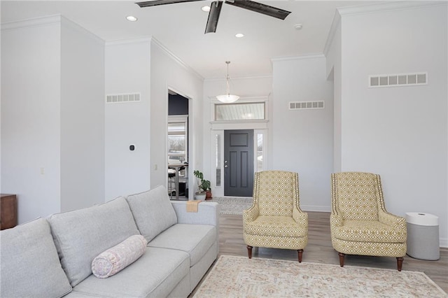 living room with wood-type flooring, ornamental molding, and ceiling fan