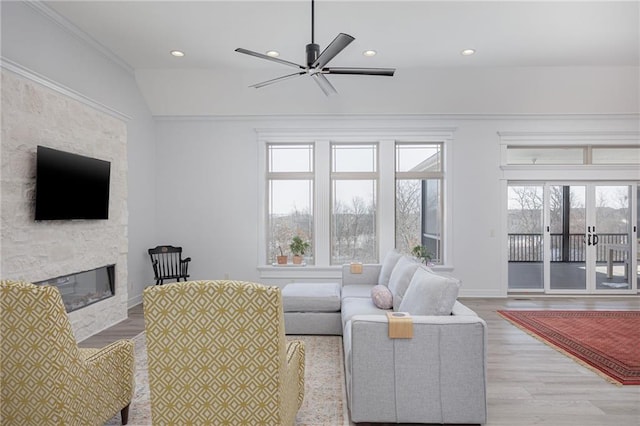 living room featuring lofted ceiling, ornamental molding, ceiling fan, a fireplace, and light hardwood / wood-style floors