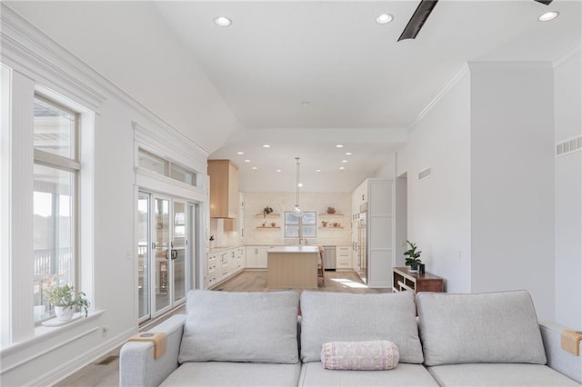 living room featuring crown molding, vaulted ceiling, and light hardwood / wood-style floors