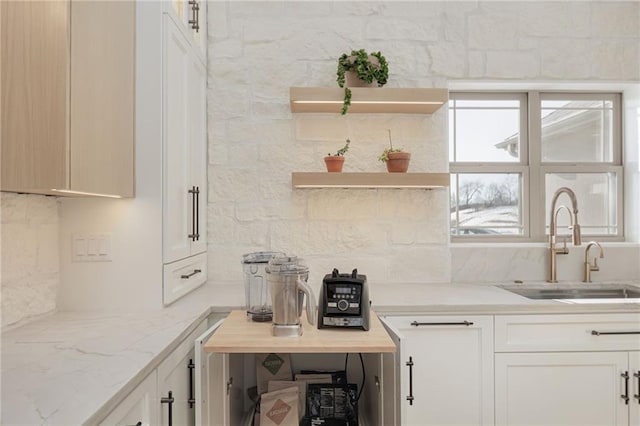 kitchen with tasteful backsplash, light stone countertops, and sink