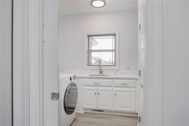 laundry area with cabinets, washer / dryer, sink, and light wood-type flooring