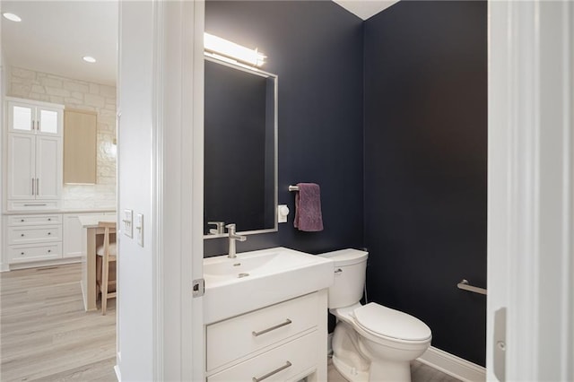 bathroom featuring vanity, toilet, wood-type flooring, and backsplash