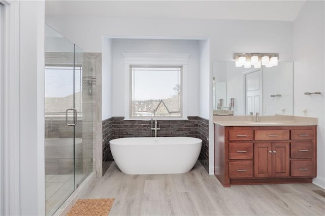 bathroom with vanity, wood-type flooring, independent shower and bath, and tile walls