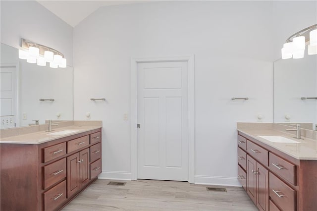 bathroom with hardwood / wood-style flooring, lofted ceiling, and vanity