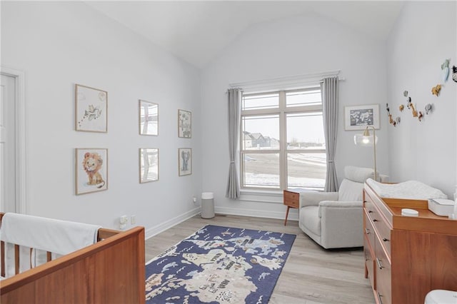 bedroom featuring vaulted ceiling, a nursery area, and light wood-type flooring