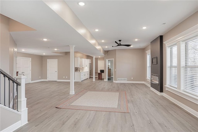 unfurnished living room featuring ceiling fan, light hardwood / wood-style flooring, and ornate columns