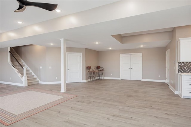 basement featuring ceiling fan and light hardwood / wood-style floors