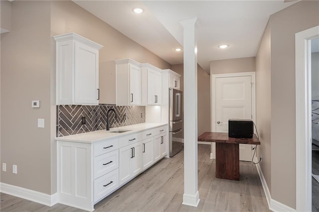 kitchen featuring backsplash, sink, white cabinets, and light wood-type flooring