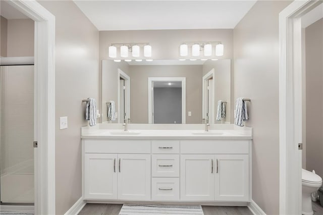 bathroom with vanity, a shower with shower door, hardwood / wood-style floors, and toilet