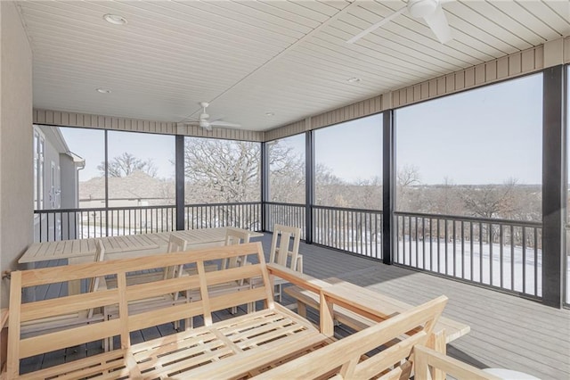 sunroom / solarium with plenty of natural light, ceiling fan, and a water view