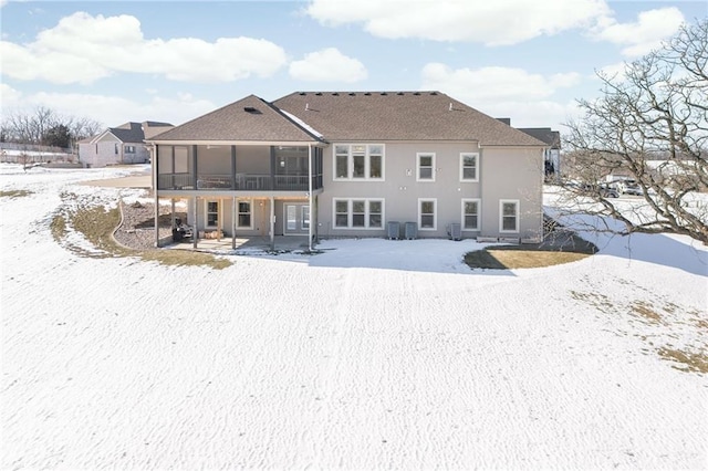 snow covered back of property with a sunroom