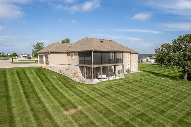 back of property featuring a yard, a sunroom, a patio area, and a garage