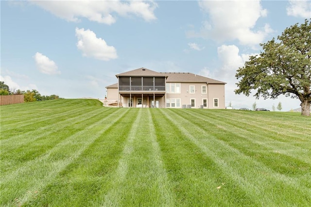 rear view of house with a lawn and a sunroom