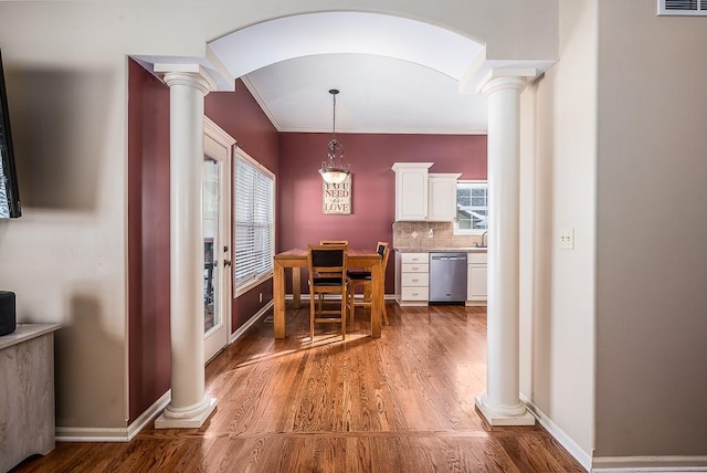 dining space featuring crown molding, hardwood / wood-style flooring, and decorative columns