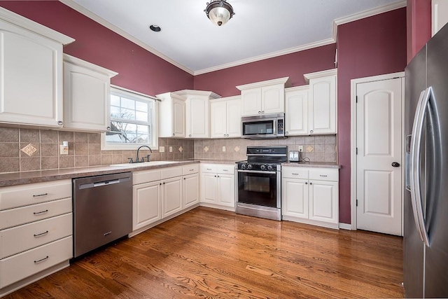 kitchen with stainless steel appliances, dark hardwood / wood-style floors, backsplash, white cabinets, and sink