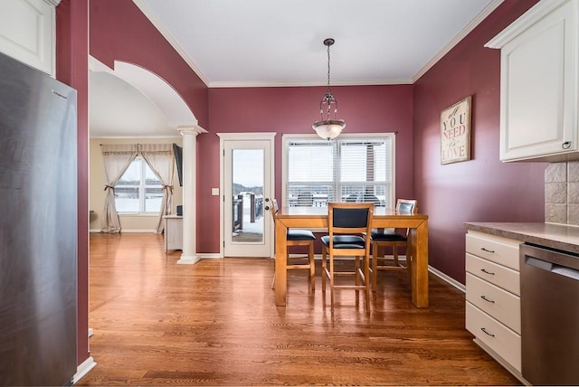 dining area with hardwood / wood-style flooring, ornamental molding, and decorative columns