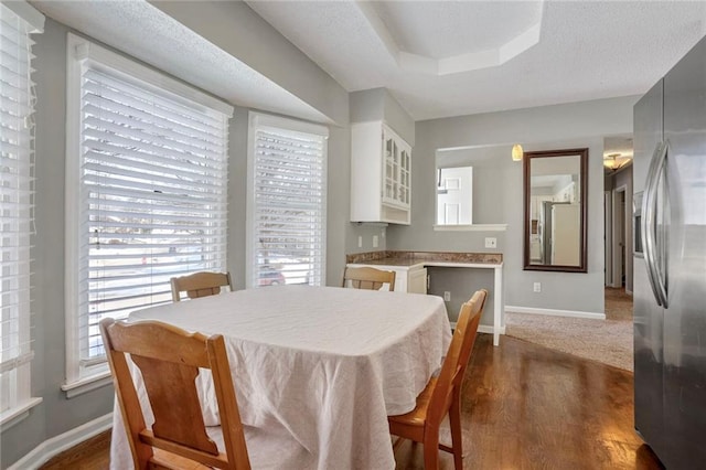 dining area with dark wood-type flooring and a tray ceiling