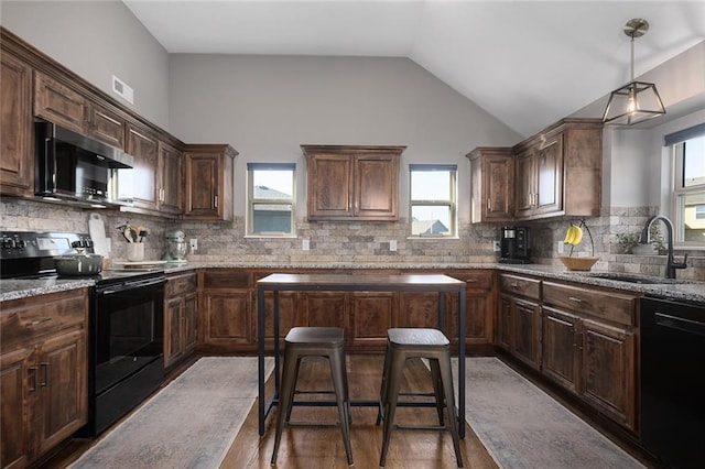 kitchen featuring sink, vaulted ceiling, light stone counters, a kitchen bar, and black appliances