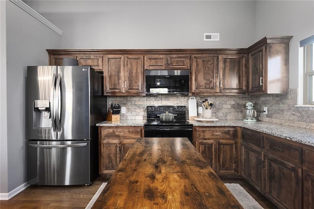 kitchen featuring dark brown cabinets, black electric range oven, light stone counters, and stainless steel refrigerator with ice dispenser