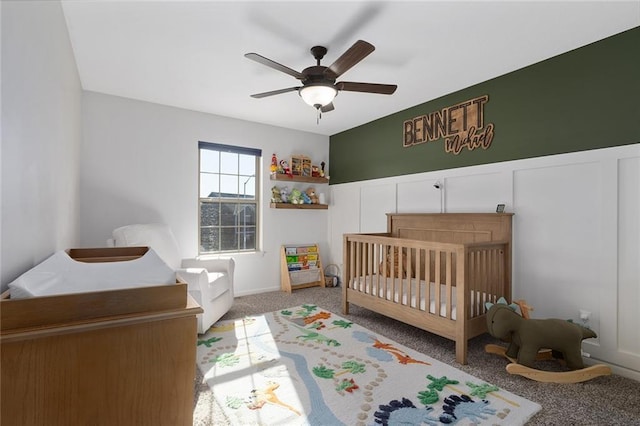 bedroom featuring ceiling fan, light colored carpet, and a crib