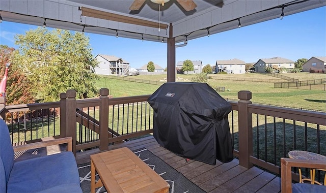 wooden terrace featuring ceiling fan, a yard, and a grill