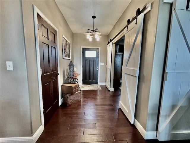 doorway to outside featuring a notable chandelier, a barn door, and dark wood-type flooring