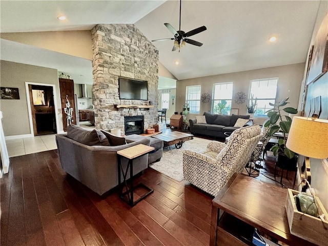 living room featuring wood-type flooring, a stone fireplace, ceiling fan, and high vaulted ceiling