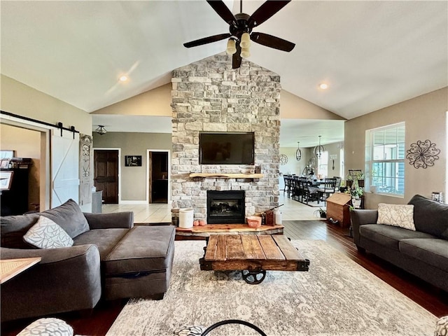 living room featuring ceiling fan, wood-type flooring, a barn door, and high vaulted ceiling