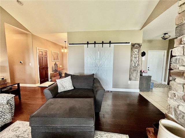 living room featuring dark hardwood / wood-style floors, a barn door, and vaulted ceiling